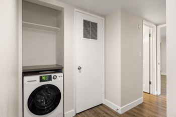 A white washing machine is in a small laundry room.